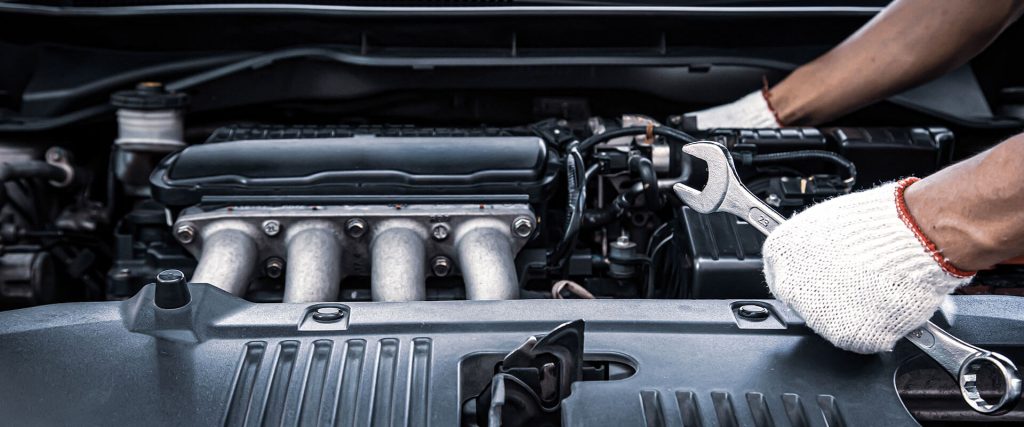 Mechanic using a wrench to perform engine maintenance, emphasizing vehicle care and transmission services at Guaranteed Auto Air & Repair in Rockledge, FL.